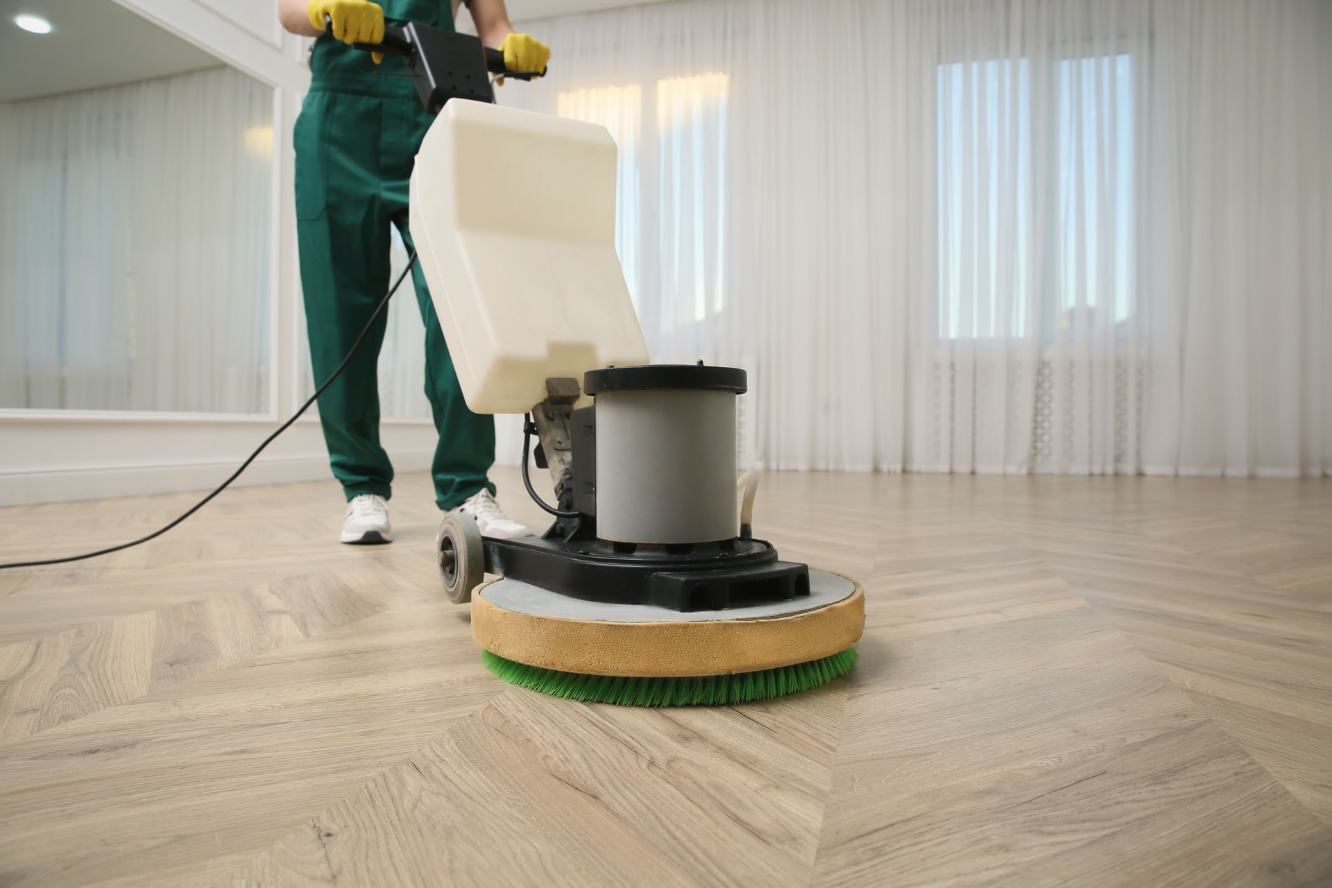 Professional janitor cleaning parquet floor with polishing machine indoors, closeup. Space for text